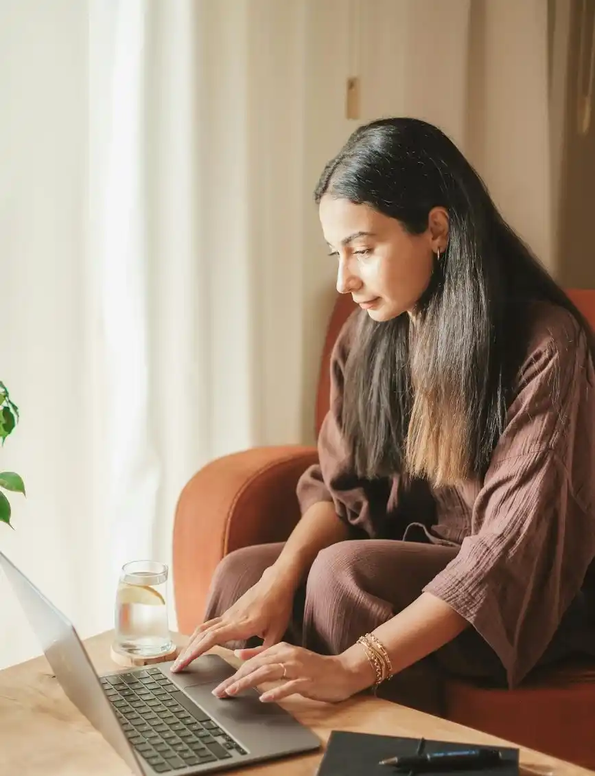 Joven mujer frente a su laptop navegando una página de universidad en línea